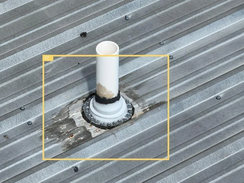 Aerial photo of a vent pipe penetration on the CrossFit eXalted roof showing pooled water and debris accumulation around the boot