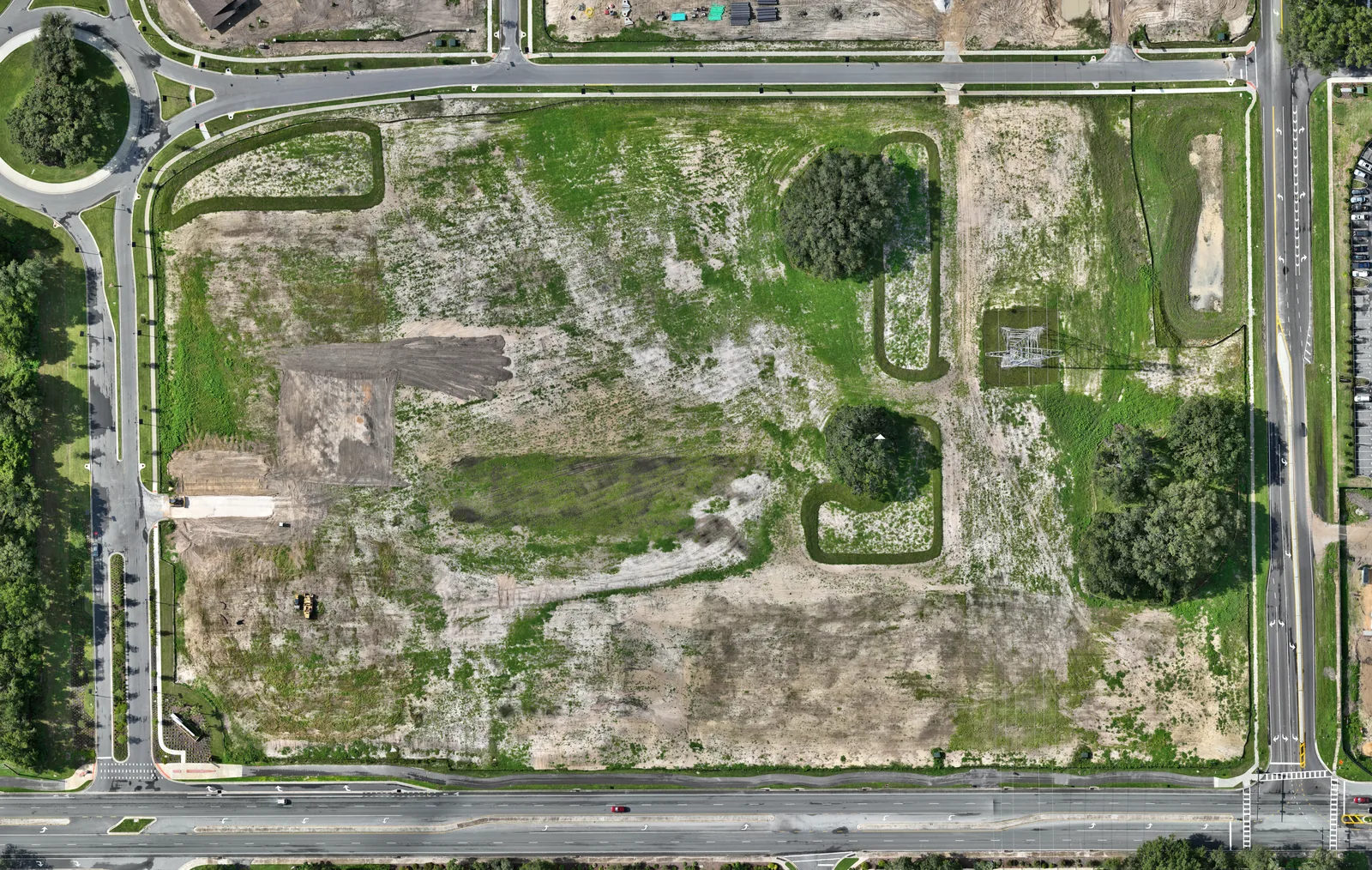 Top-down orthomosaic aerial map of the Walmart Supercenter construction site in Lady Lake, Florida at the start of weekly aerial documentation (August 24, 2025), showing the cleared and rough-graded parcel with landscaped berms, two preserved tree clusters, a high-voltage transmission tower, scattered soil stockpiles, and a single piece of earthmoving equipment. No vertical construction has started.