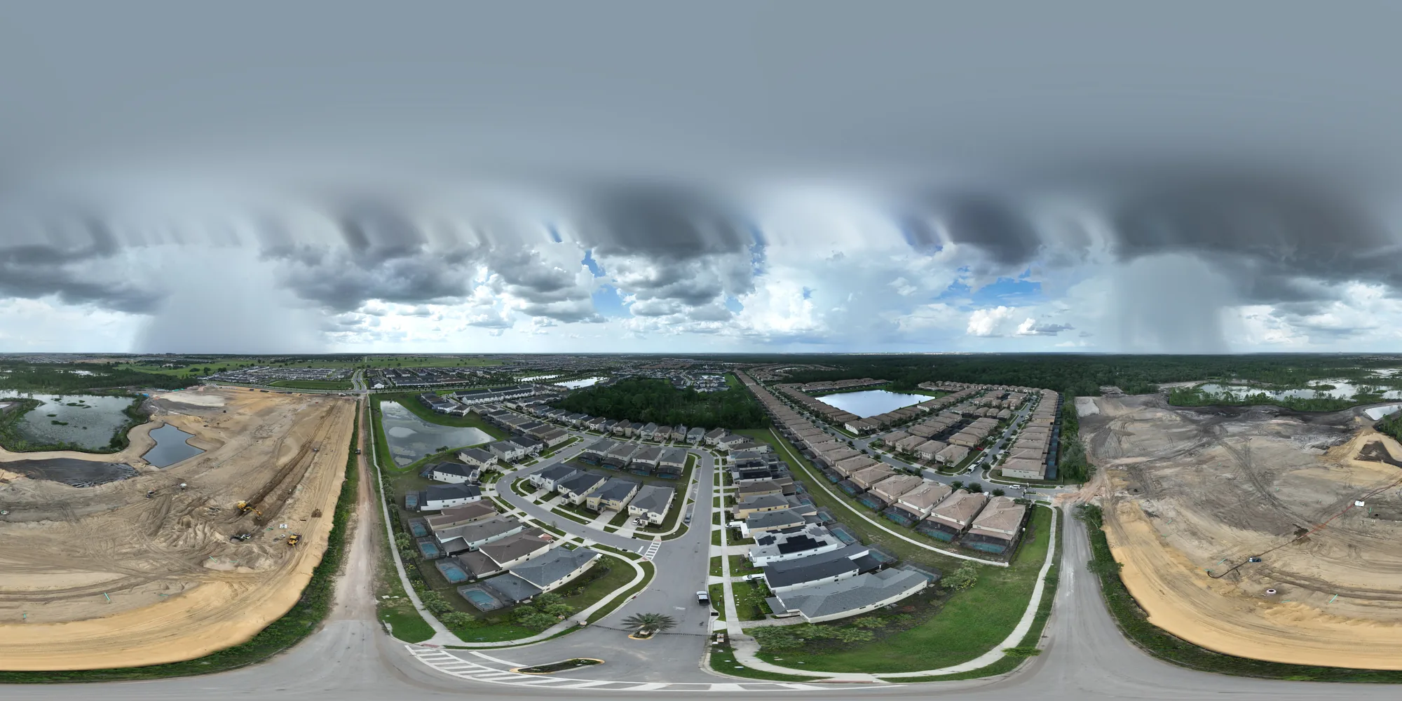 Equirectangular aerial panorama of a master-planned residential community in Central Florida in active expansion, showing completed homes in the center with active earthwork on the flanks.